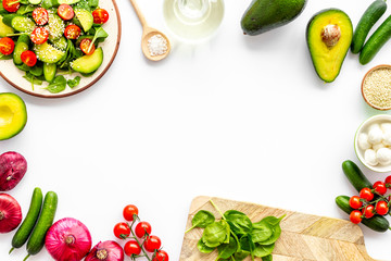 Preparing fresh salad. Vegetables, greens, spices on white background top view copy space frame