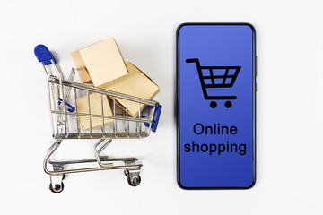 Supermarket cart with boxes and smartphone on white background. Online shopping.