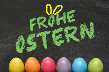 Ostereier und eine Kreidetafel mit dem Slogan Frohe Ostern