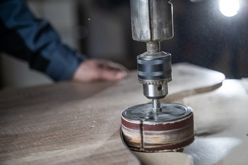 Carpenter polishes a wooden parts on a grinding machine.
