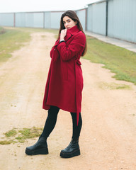 Fototapeta premium Fashion woman portrait of young pretty girl posing in a rural scene in Europe. Winter and spring fashion, wearing a red jacket.