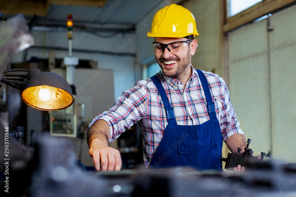 Wall mural Worker in uniform operating in manual lathe in metal industry factory.