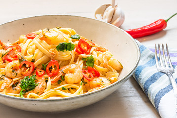 Linguine with shrimps on a rustic plate close-up - traditional Mediterranean pasta with seafood, Italian cuisine.
