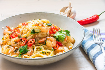 Linguine with shrimps on a rustic plate close-up - traditional Mediterranean pasta with seafood, Italian cuisine.
