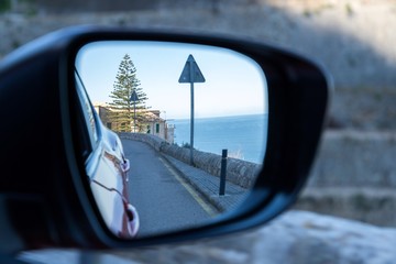  Car driving travel concept - car rear view mirror view of a mountain road with rocks and trees 