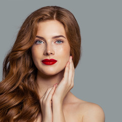 Fototapeta premium Attractive redhead girl with red lips makeup looking at camera
