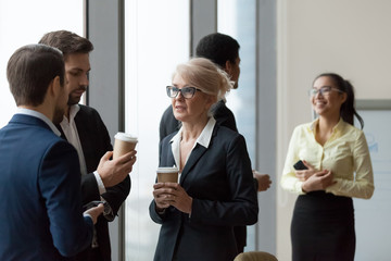 Diverse workers having conversation standing in office at work break