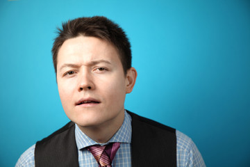 Young attractive businessman businessman in suit on blue background holding his head with his hand, mistake or surprise.