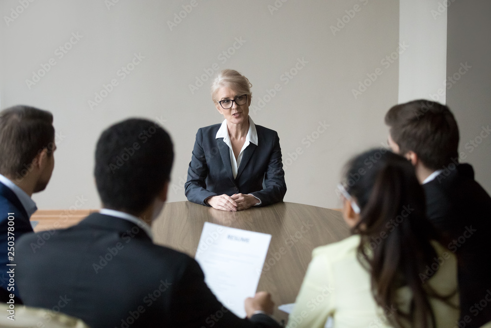 Poster middle-aged confident applicant talking to hr managers during job interview