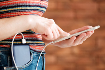 Woman using smart phone while charging on the power bank.