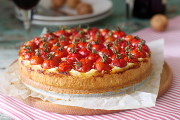 Tart, pie or cheesecake with cottage cheese and tomatoes, served with red wine on a wooden background.