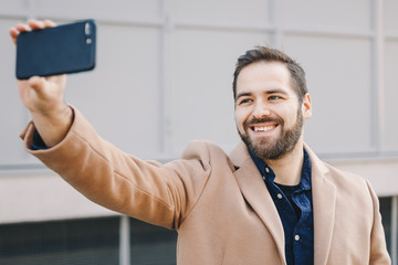 Close-up portrait of attractive and modern young man having a video call over his mobile phone,...