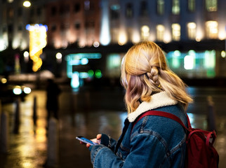 Young girl on the street with a mobile phone in his hands. View from the back.