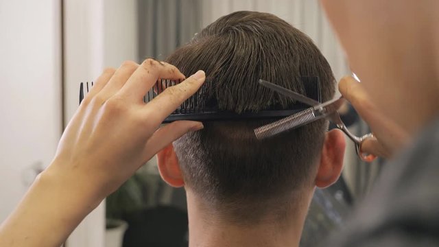 back view of female barber haircut doing male hair style, slow motion