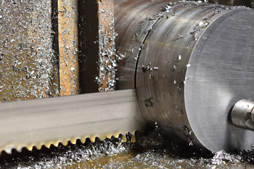 The process of cutting metal with an electric saw in a factory. Electric saw cuts round metal