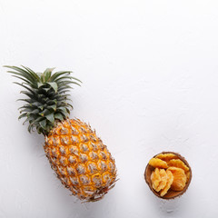 Dried pineapple rings and whole fresh pineapple on white background. Top view, flat lay, copy space.