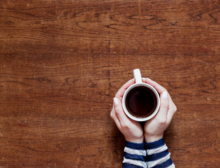 Fototapeta na wymiar hands holding a cup of coffee on a wooden background