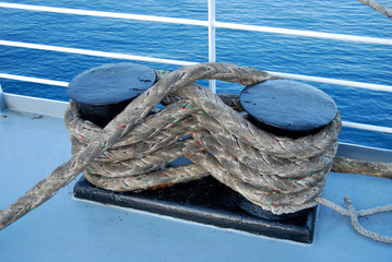 Bundle of marine ropes on the mooring bollard, mooring rope with a knotted end tied around a cleat 