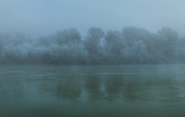 Obraz na płótnie Canvas River in the fog. Forest by the river in hoarfrost, hoarfrost. Background water of the river and the forest on the shore in the fog.