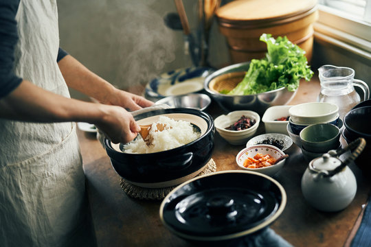 土鍋で炊いたご飯をかき混ぜる女性