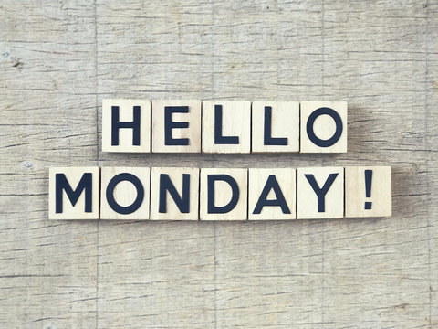 HELLO MONDAY written on wooden blocks and arranged on a wooden table.