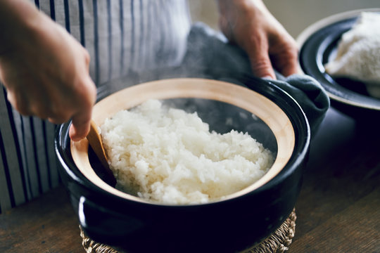 土鍋で炊いたご飯をかき混ぜる女性