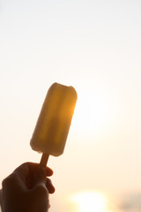 Ice cream popsicle stick in hand to the hot summer sky sea.