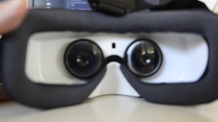 The VR 360 viewer is approached to the face. From the point of view of the wearer, we see the inside with the two lenses approaching intimately our eyes. Blurred background. 25fps 4K video.