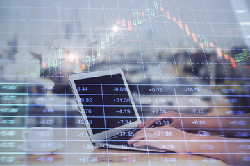 Hands typing on laptop. Business and Financial concept. Double exposure of stock market charts.