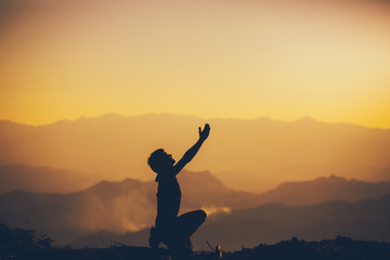Man sitting and worshipping God at sunset background. christian silhouette concept.