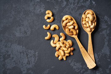cashew nuts   in two wooden spoons on black table ,with copy space ,Top view