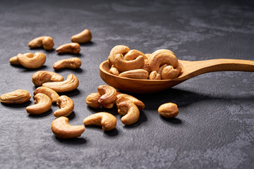 cashew nuts  in wooden spoon  on black table,close-up