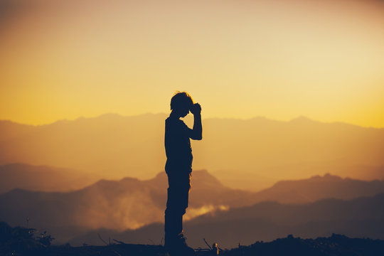 Man standing praying and worshipping God at sunset background. christian silhouette concept.