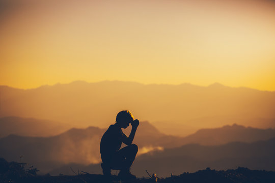 Man sitting praying and worshipping God at sunset background. christian silhouette concept.