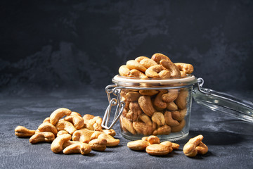 Cashew nuts in an open glass jar on black table ,close-up