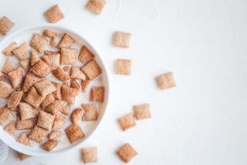 Dry breakfast cereal pads with milk on a white concrete background