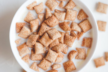 Dry breakfast cereal pads with milk on a white concrete background