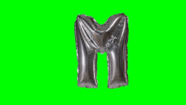 Big Letter M from alphabet helium silver balloon floating on green screen