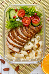 Lunch box: rotini with baked chicken breast and salad. Top view, flat lay. Delicious healthy lunch. The concept of healthy eating.