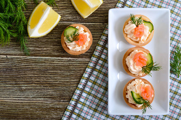 Tartlets with cream cheese and salted salmon on a white plate. Tasty light snack for a party. Finger Food.