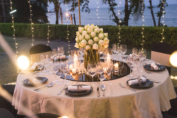 Dinner table setup for wedding ceremony at outdoor in night time with beach view, decorate with lotus flowers in Indian style