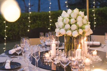 Dinner table setup for wedding ceremony at outdoor in night time with beach view, decorate with lotus flowers in Indian style