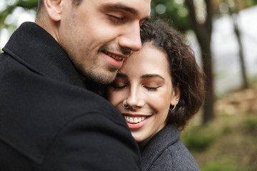 Portrait closeup of happy people man and woman 20s hugging, while walking through green park