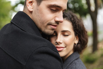 Fototapeta premium Portrait closeup of beautiful people man and woman 20s hugging, while walking through green park