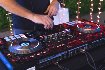 Obraz premium DJ is mixing some music with controller at outdoor night party, by moving hand so fast to set many button