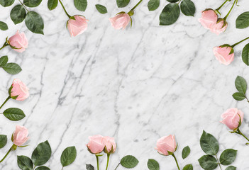 Frame of pink roses and castings on a marble background. Beautiful fashionable background. Flat lay.  Floral background.Top view. Copy space. Mock-up