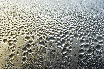 Dew drops on the window glass with blurry sun