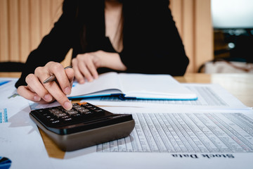 Business woman using calculator for analyze with stock data document. Business finance concept.