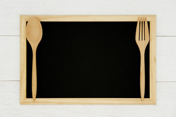Blank chalkboard with wooden spoon and fork on white wood plank background. Styled stock photography for cookbook, food blog posts and social media content. 