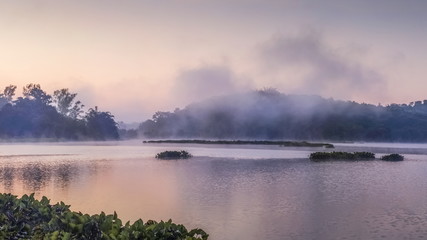 Fototapeta na wymiar sunrise at Chiang Saen Lake, beautiful lake view misty morning of the hill around with soft mist moving above the water and colorful sun light in the sky background, Chiang Rai, northern of Thailand.